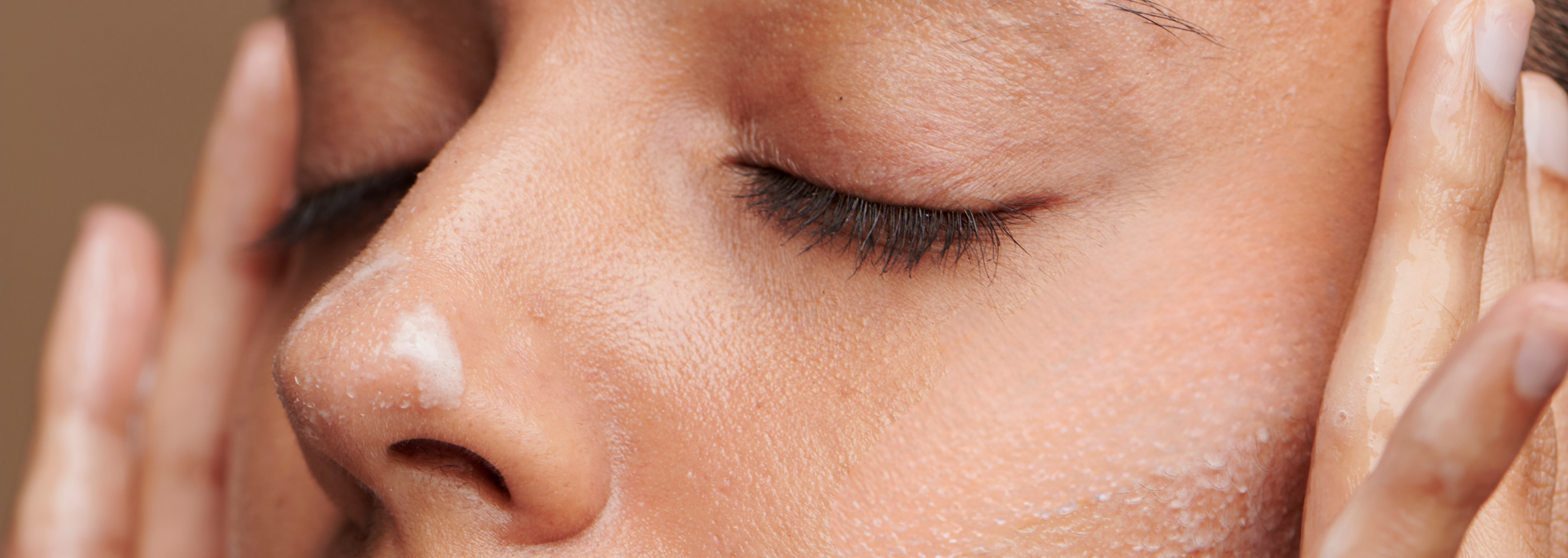 Woman with closed eyes applying product to her face background image